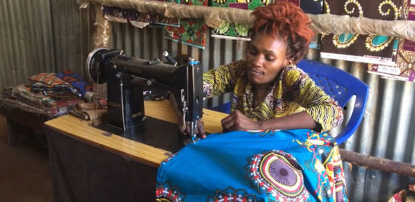Una refugiada discapacitada de República Democrática del Congo trabaja con su máquina de coser haciendo trajes.