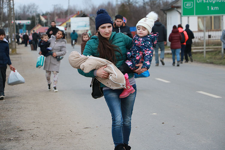 Madre ucraniana carga en brazos con sus dos hijos