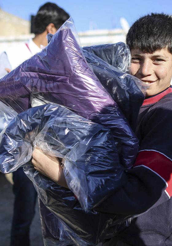 Niño refugiado recogiendo materiales de primera necesidad