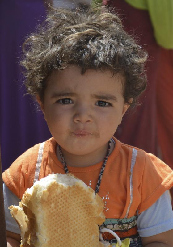 Niño refugiado con una hogaza de pan