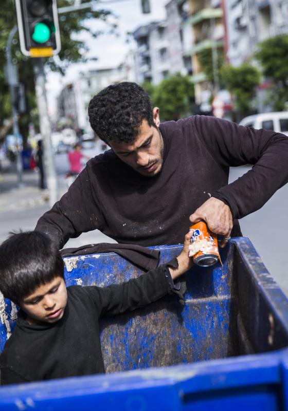 Refugiados sirios buscando en la basura Refugiado con brazo amputado buscando en la basura