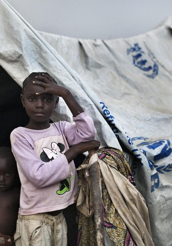 Dos niños refugiados junto a una tienda de ACNUR