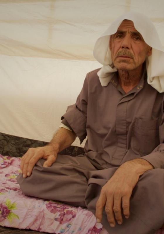 Señor iraqui sentado con las piernas cruzadas Señor iraqui de 69 años refugiado